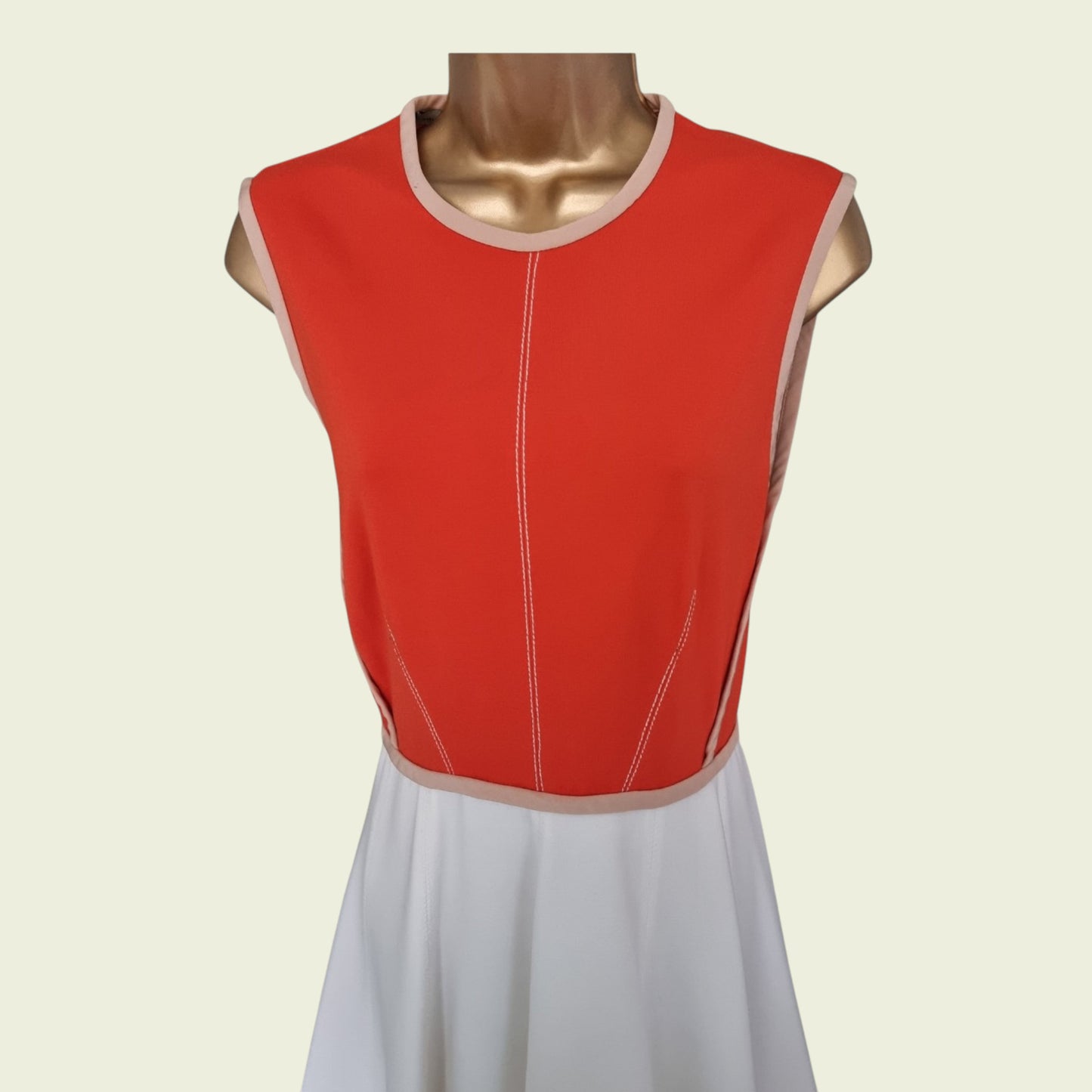 Red sleeveless dress with white trim on a mannequin against a beige background