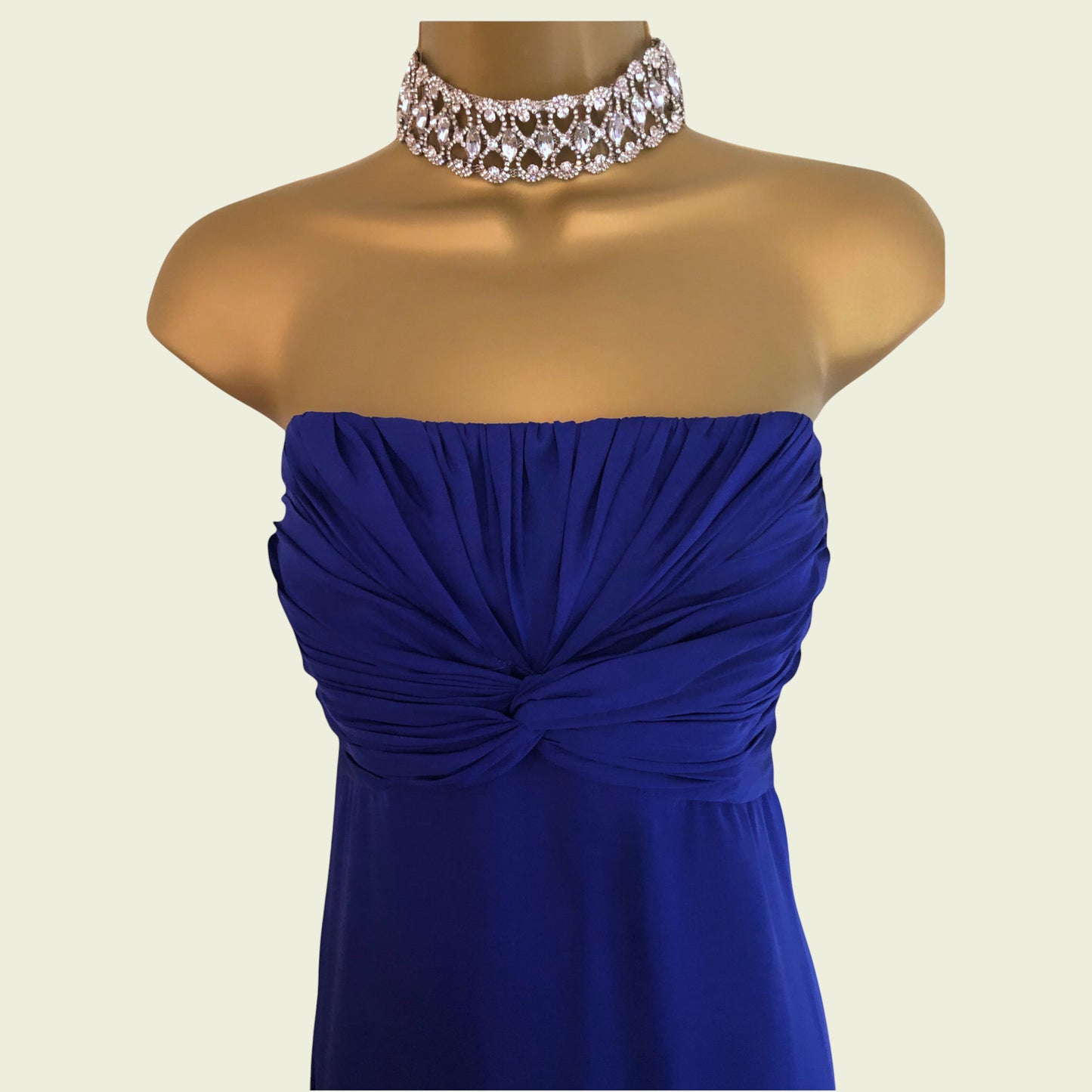Mannequin wearing a blue strapless dress with a decorative necklace on a beige background