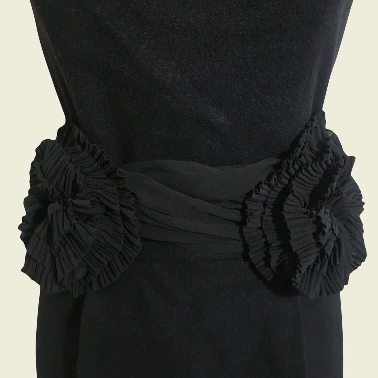 Black dress with floral embellishments on a beige background