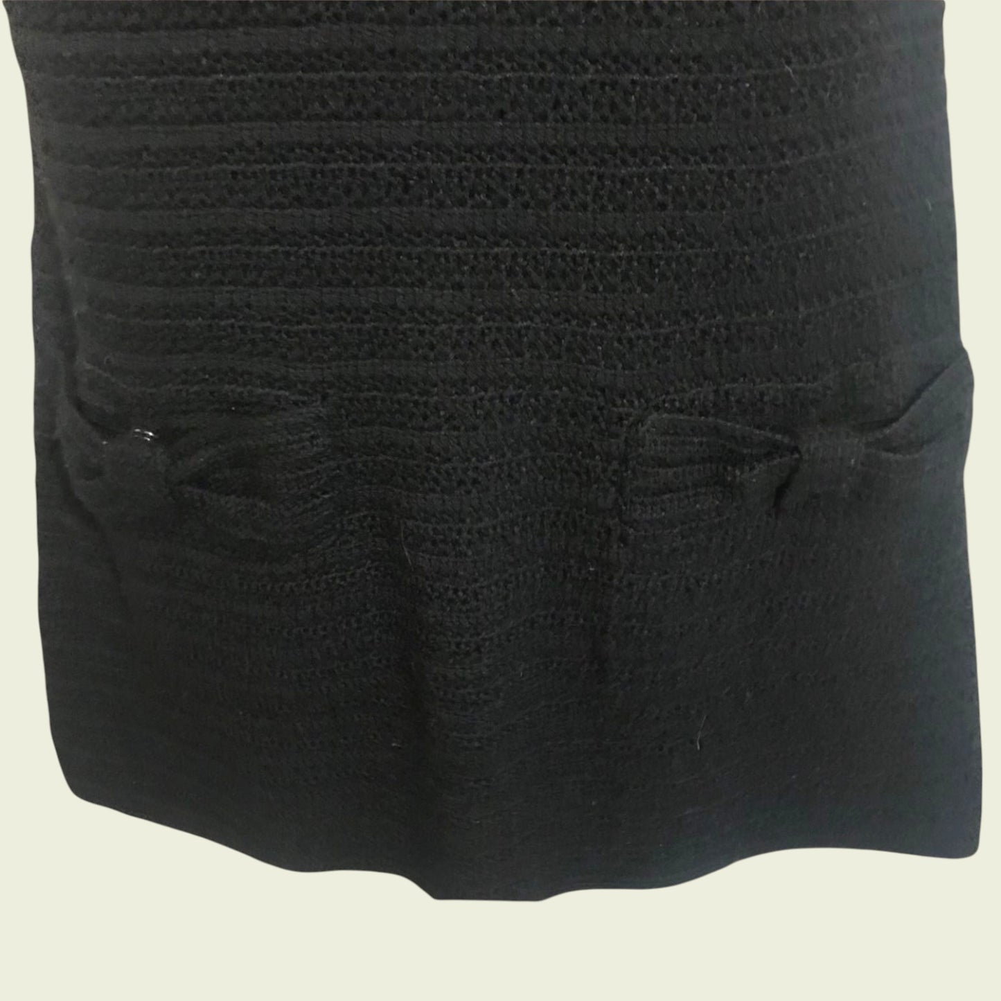 Close-up of a textured black fabric with two small bows on a beige background
