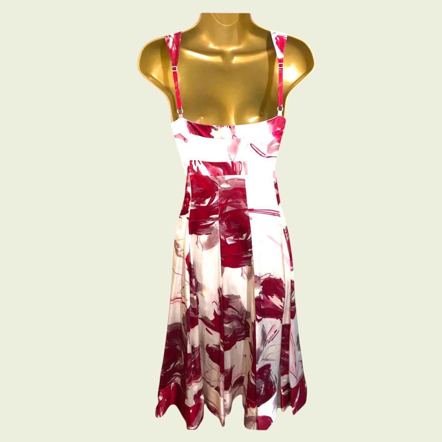 Red and white floral dress on a gold mannequin against a beige background