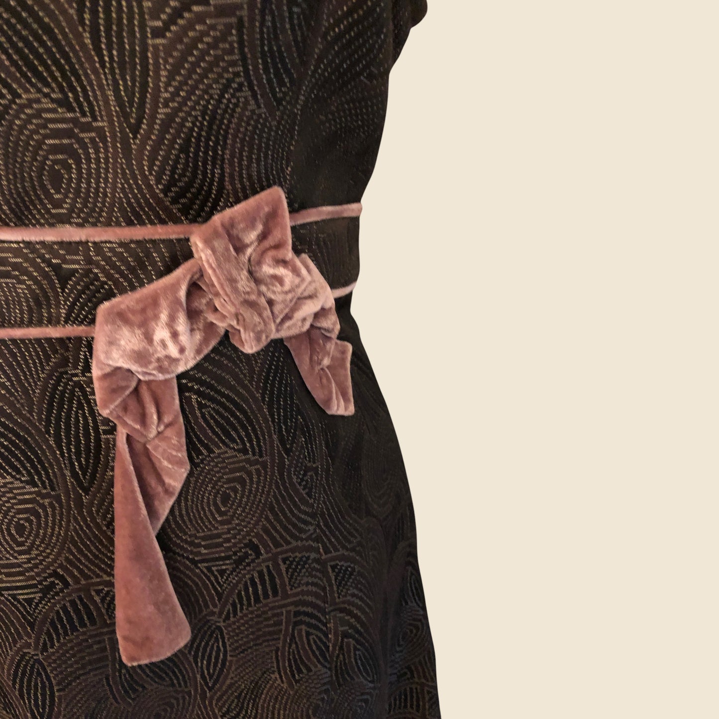 Brown patterned dress with a pink velvet belt on a beige background