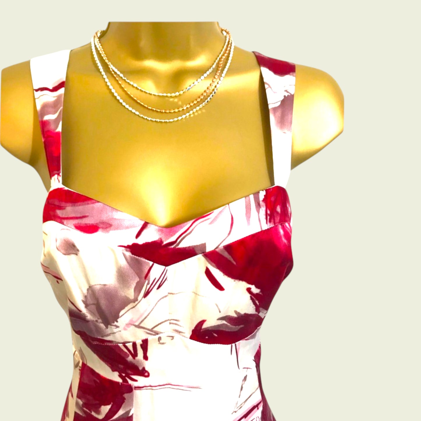 Mannequin wearing a red and white floral dress with a gold necklace on a beige background