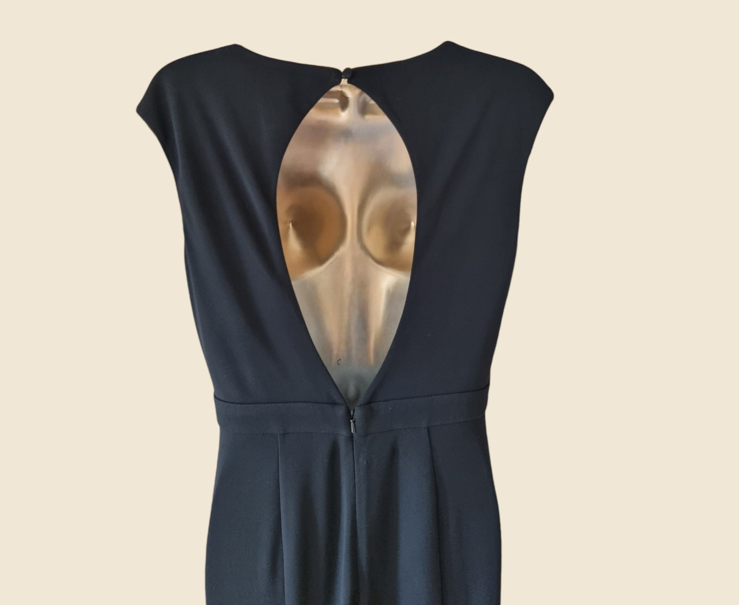 Black dress with a unique cutout design on the back against a beige background