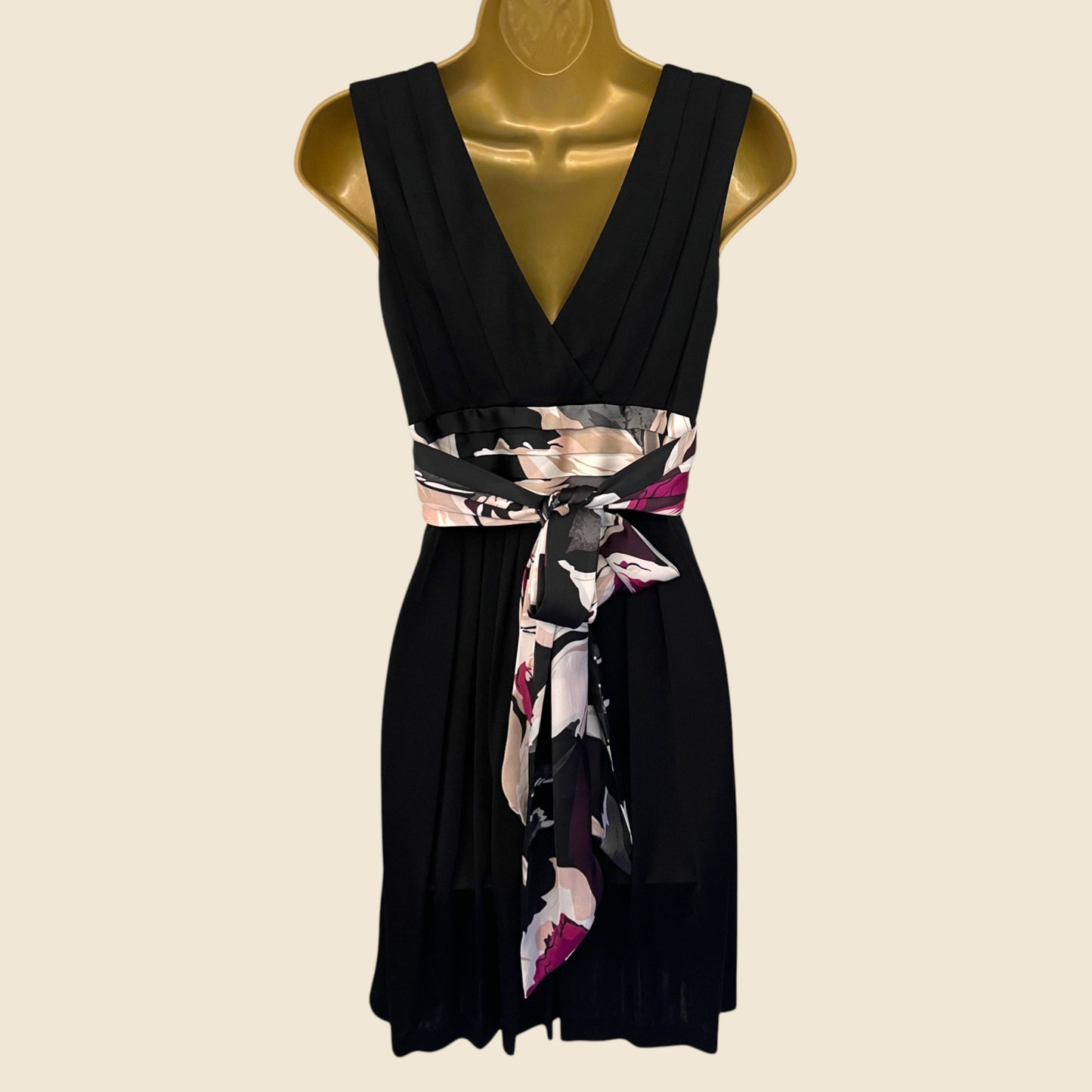 Black dress with a floral belt on a mannequin against a beige background