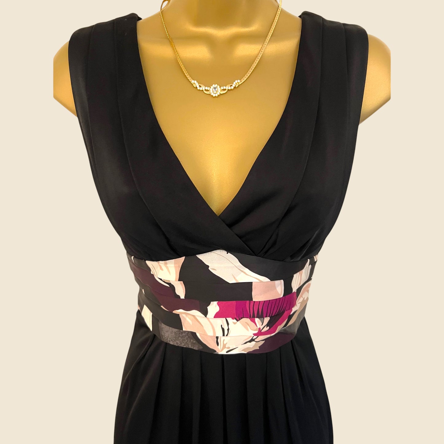 Black dress with floral patterned belt on a mannequin against a beige background