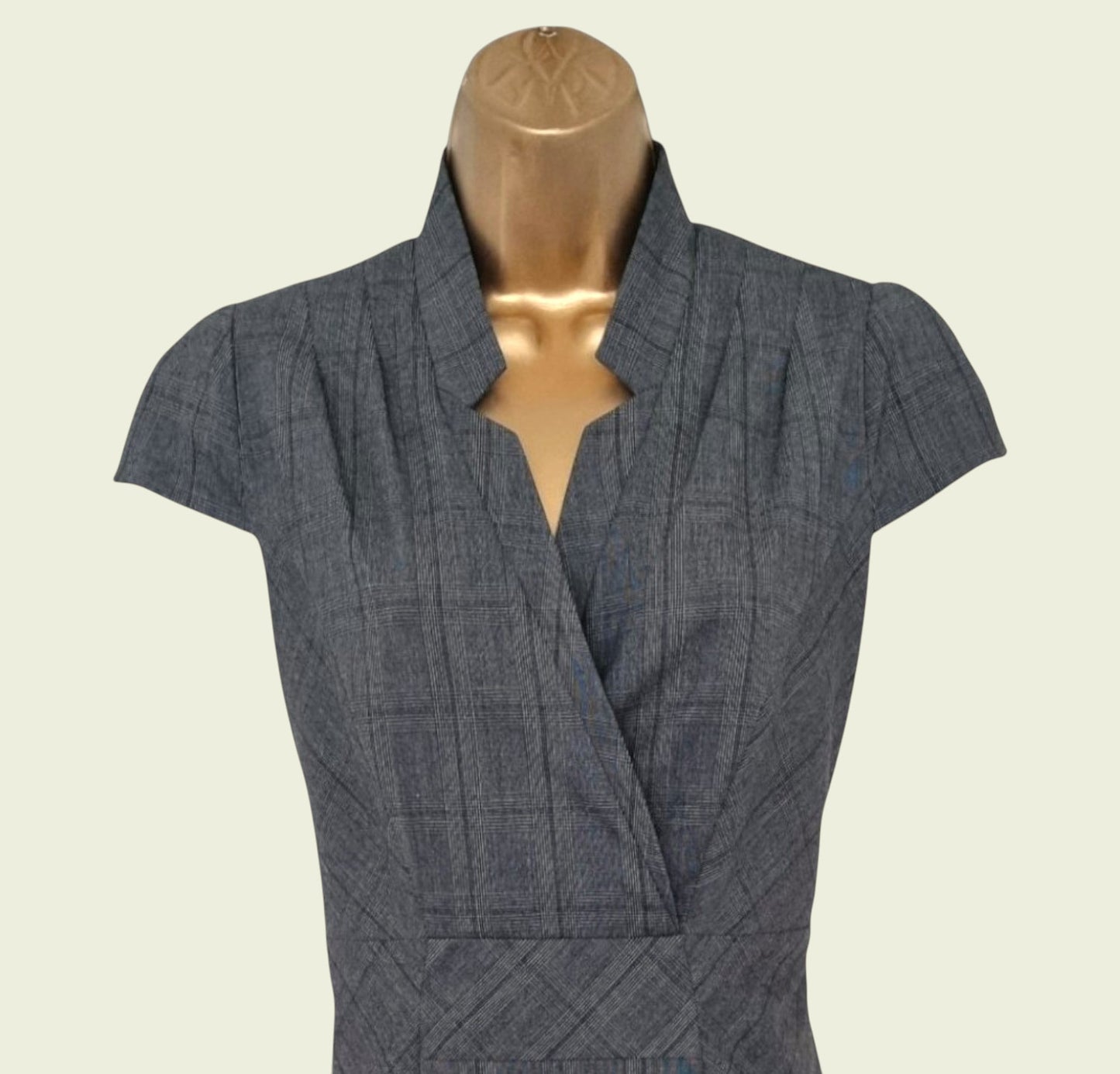 Gray checkered dress on a mannequin against a beige background