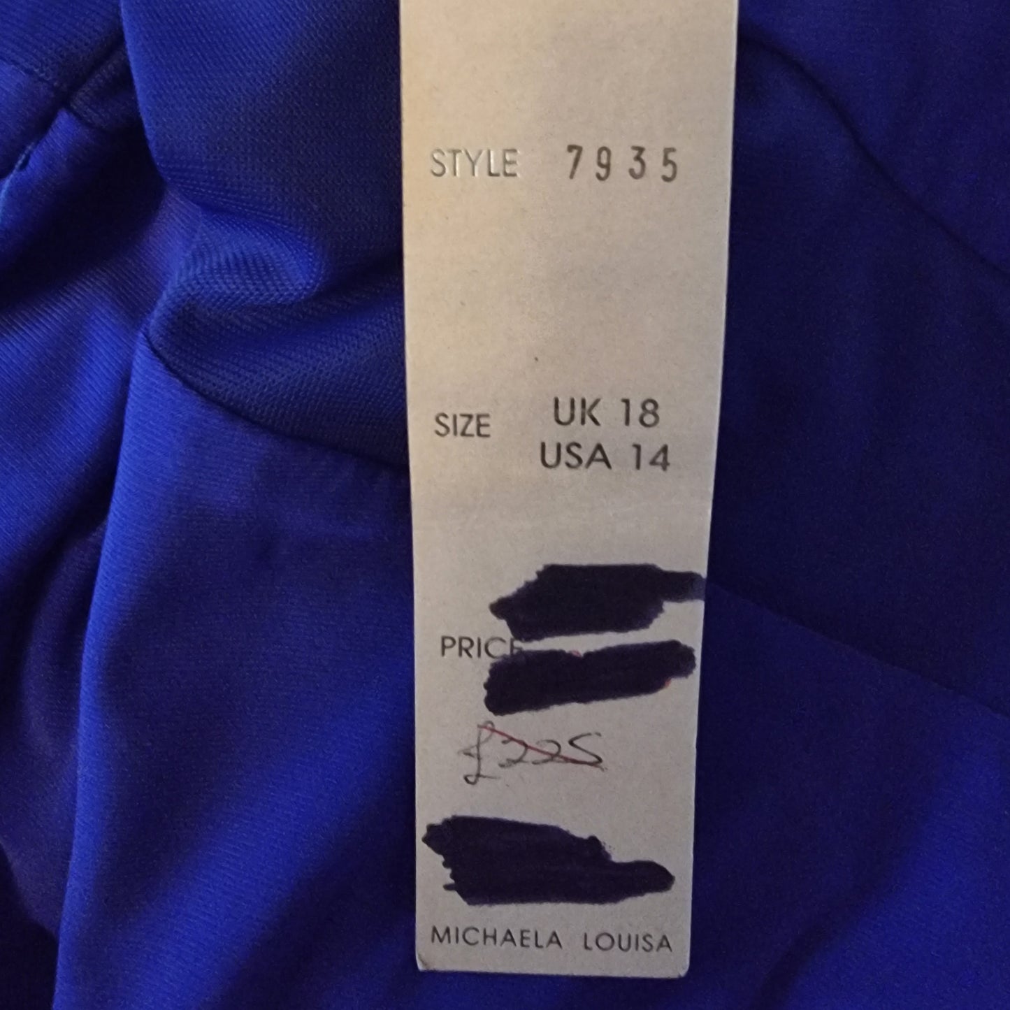 Clothing tag on a blue fabric background with size, style, and brand information.