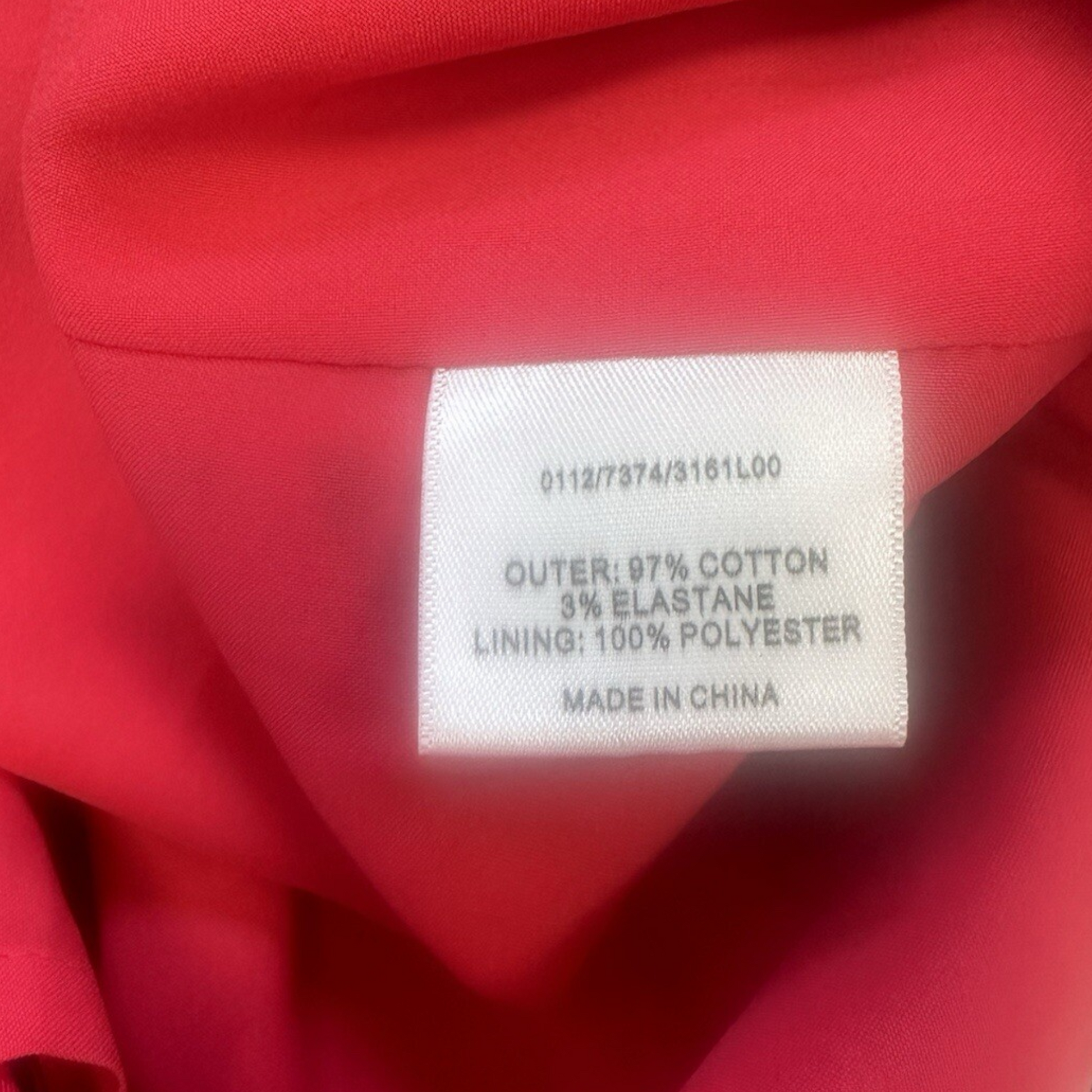 Fabric label on a red garment with text about material composition.