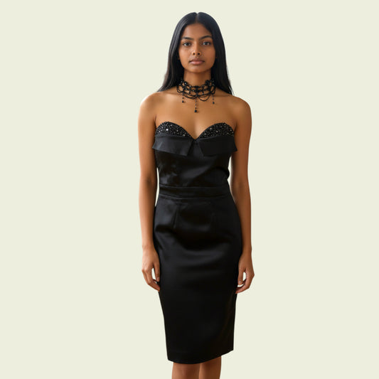 Woman wearing a black strapless dress with a bow detail on a beige background