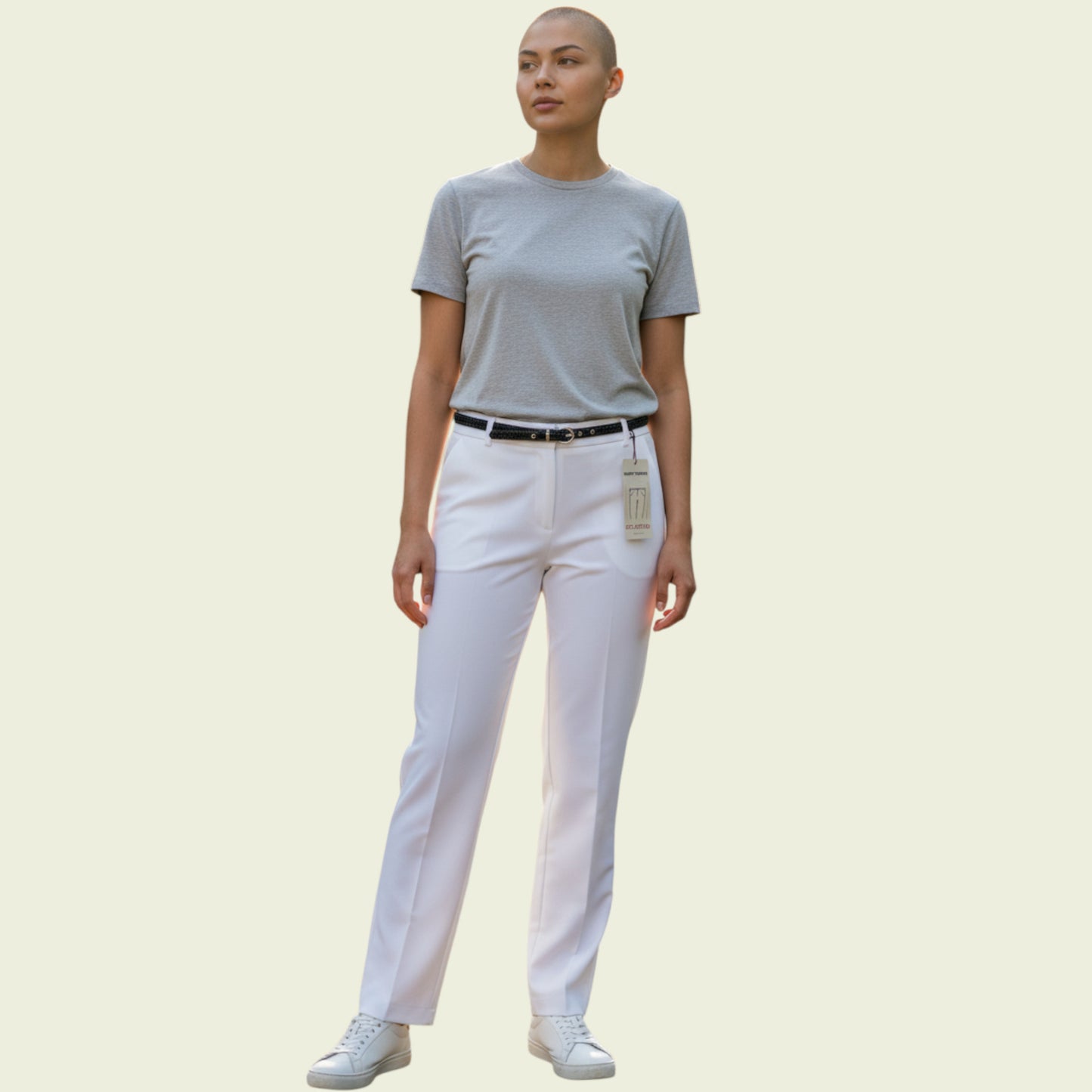 Person wearing a gray t-shirt and white pants on a beige background