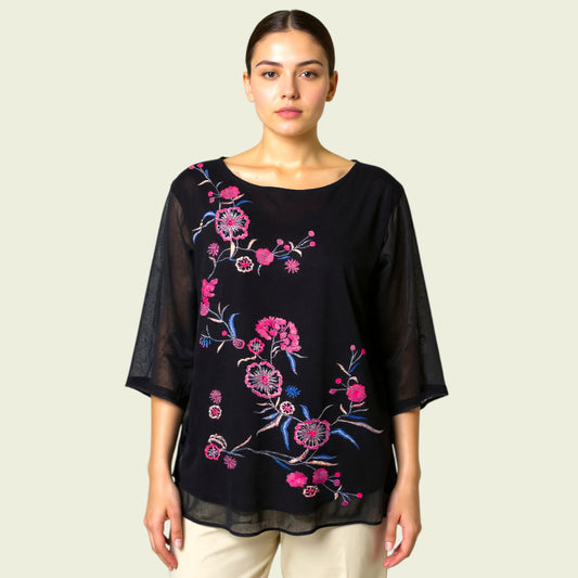 Woman wearing a black blouse with floral embroidery on a beige background