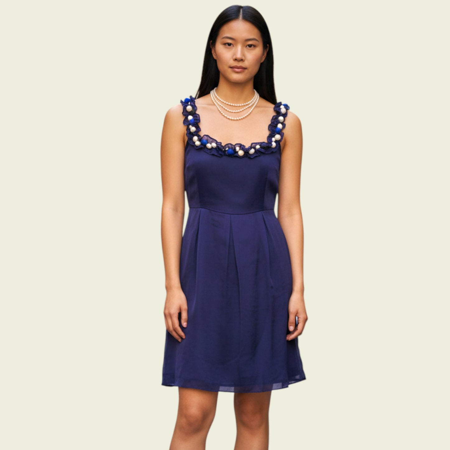 Woman wearing a navy blue dress with decorative neckline on a beige background