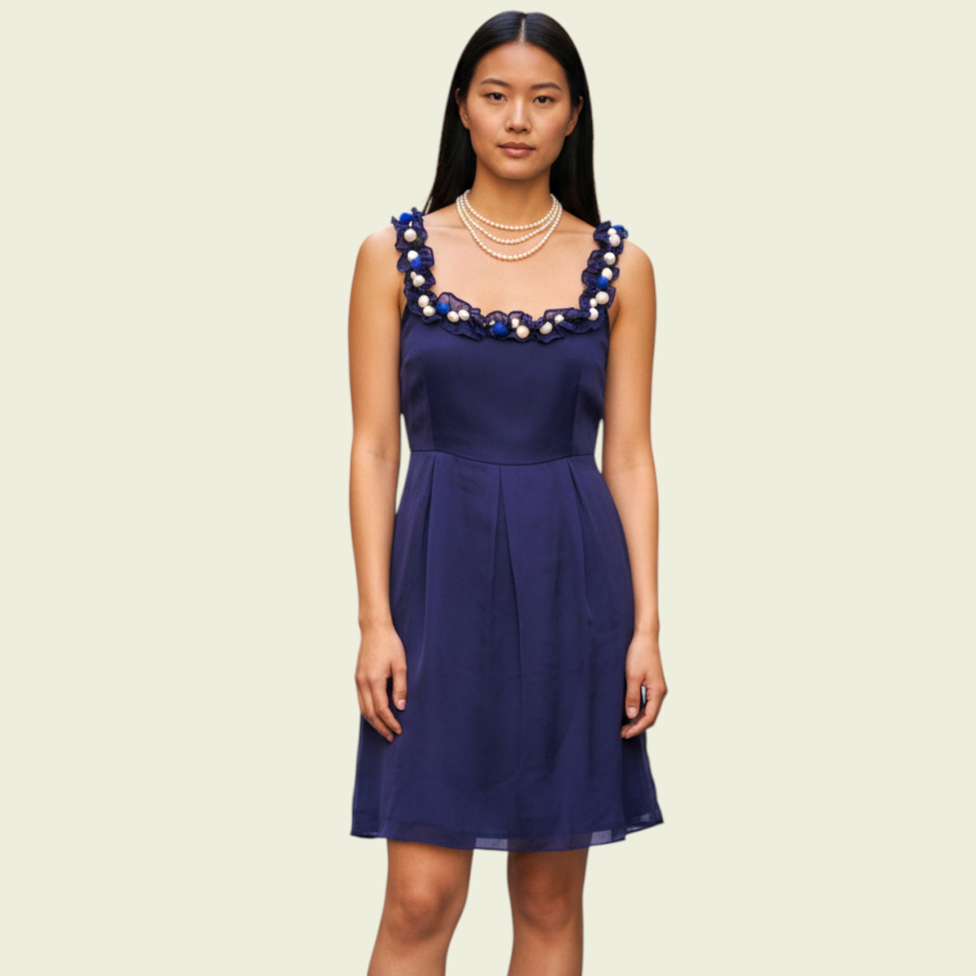 Woman wearing a navy blue dress with decorative neckline on a beige background