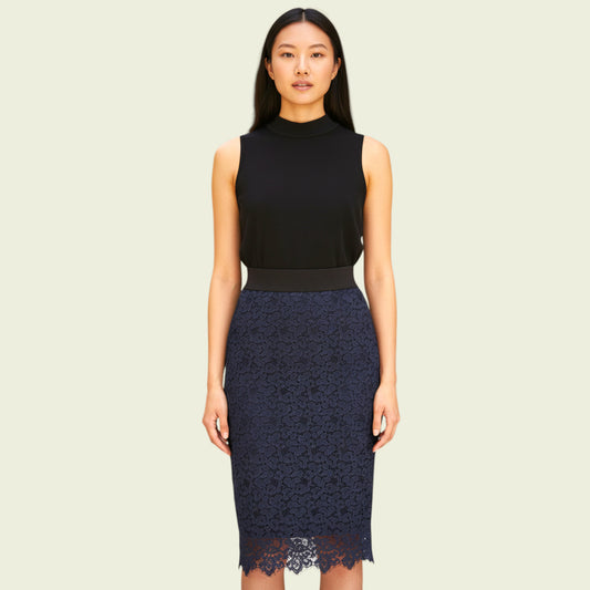 Woman wearing a black sleeveless top and navy lace skirt on a beige background