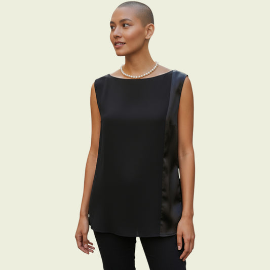 Woman wearing a black sleeveless top with a satin ribbon on a beige background