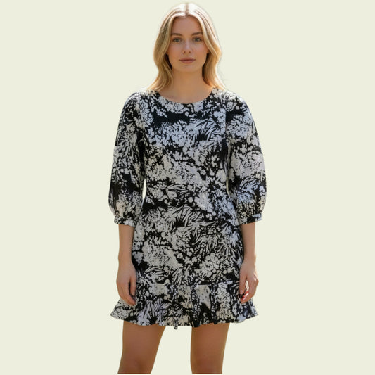 Model wearing black and white floral dress on beige background