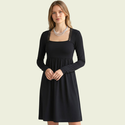 Model wearing black dress with bronze studs on beige background