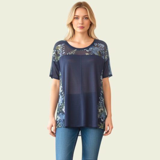 Woman wearing a navy blue top with floral lace details on a beige background