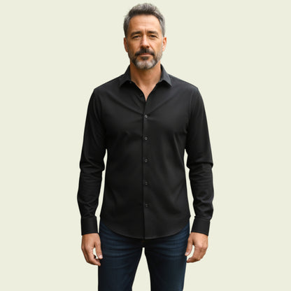 Man wearing a black dress shirt and jeans against a beige background