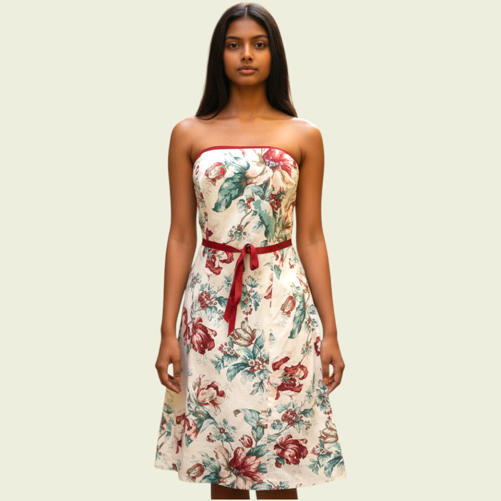 Woman wearing a strapless floral dress with a red belt on a beige background