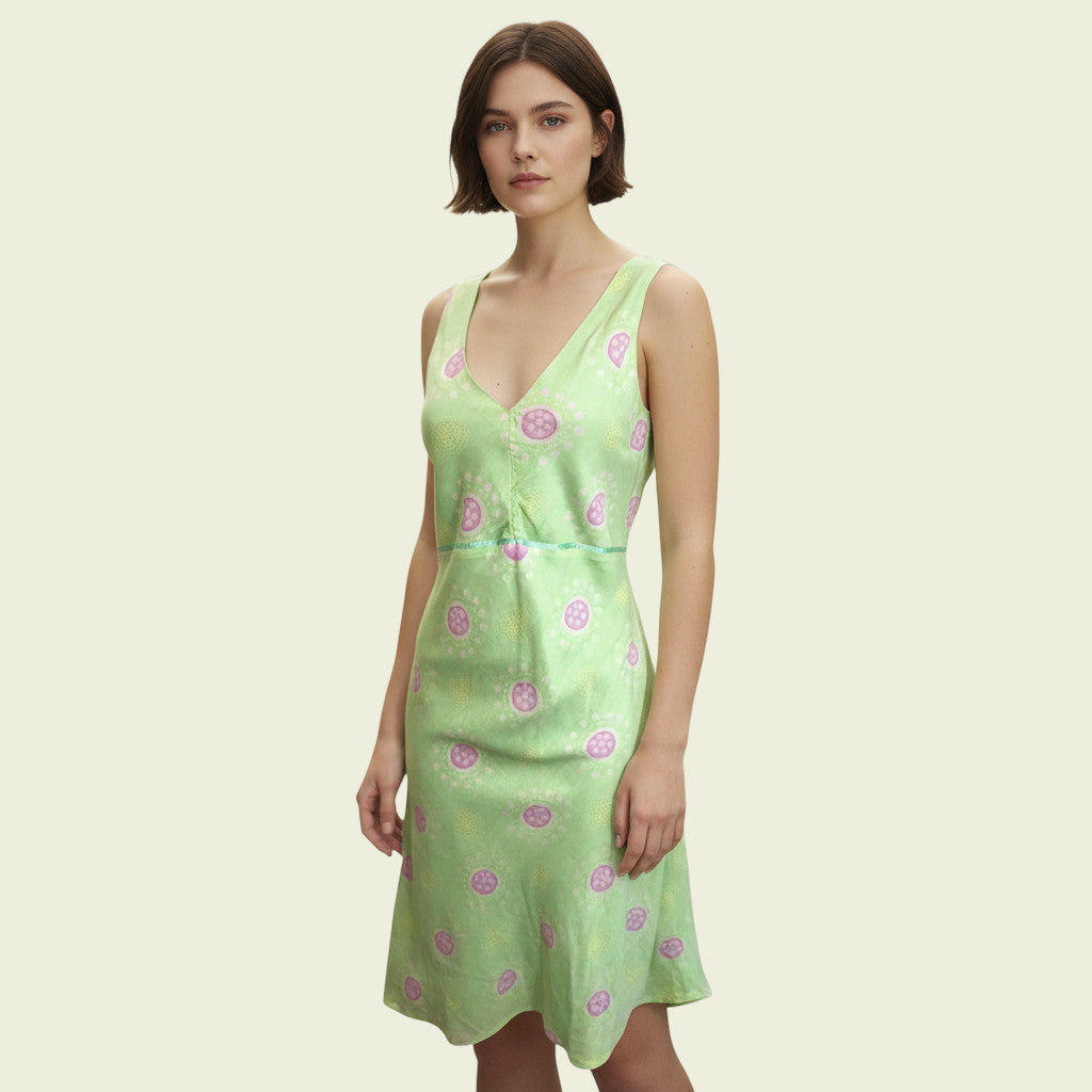 Woman wearing a light green dress with pink floral patterns on a beige background