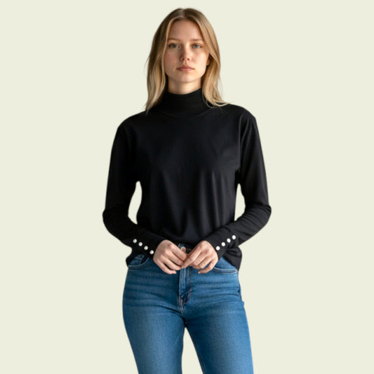 Woman wearing a black turtleneck sweater with pearl buttons and blue jeans on a beige background