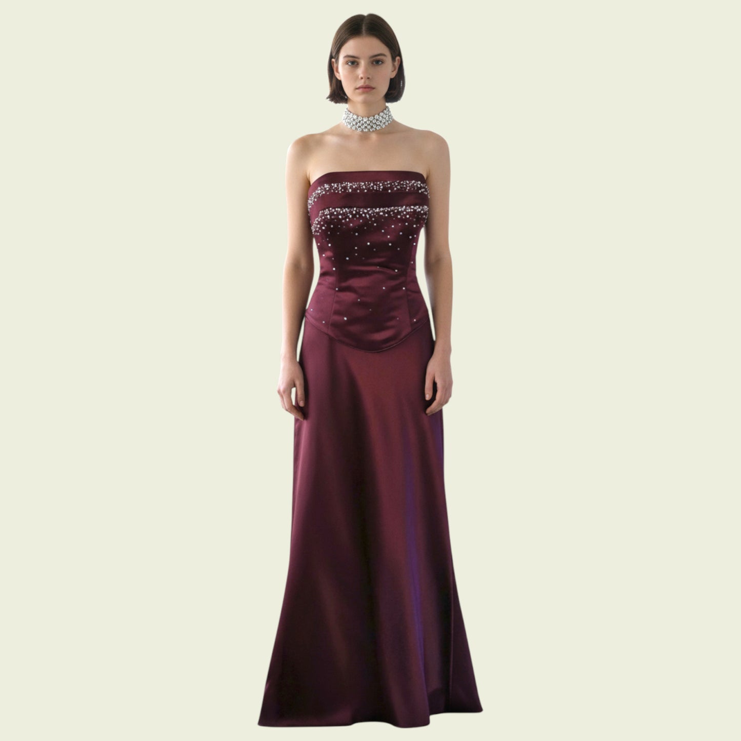 Burgundy strapless gown with beaded details on a beige background