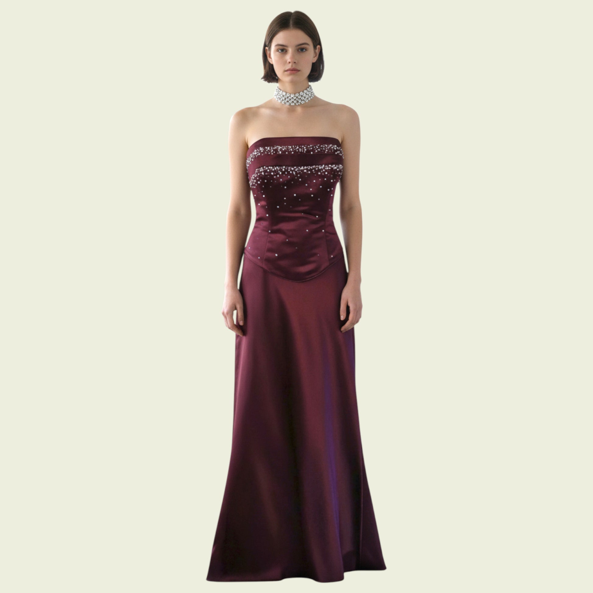 Burgundy strapless gown with beaded details on a beige background