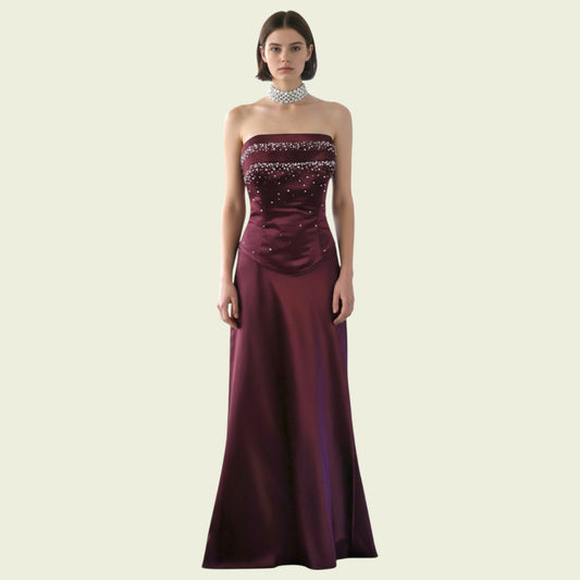 Burgundy strapless gown with beaded details on a beige background