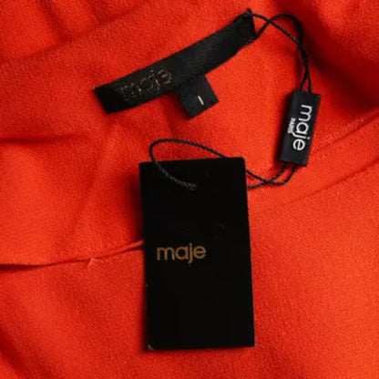 Maje branded tag on a red fabric background