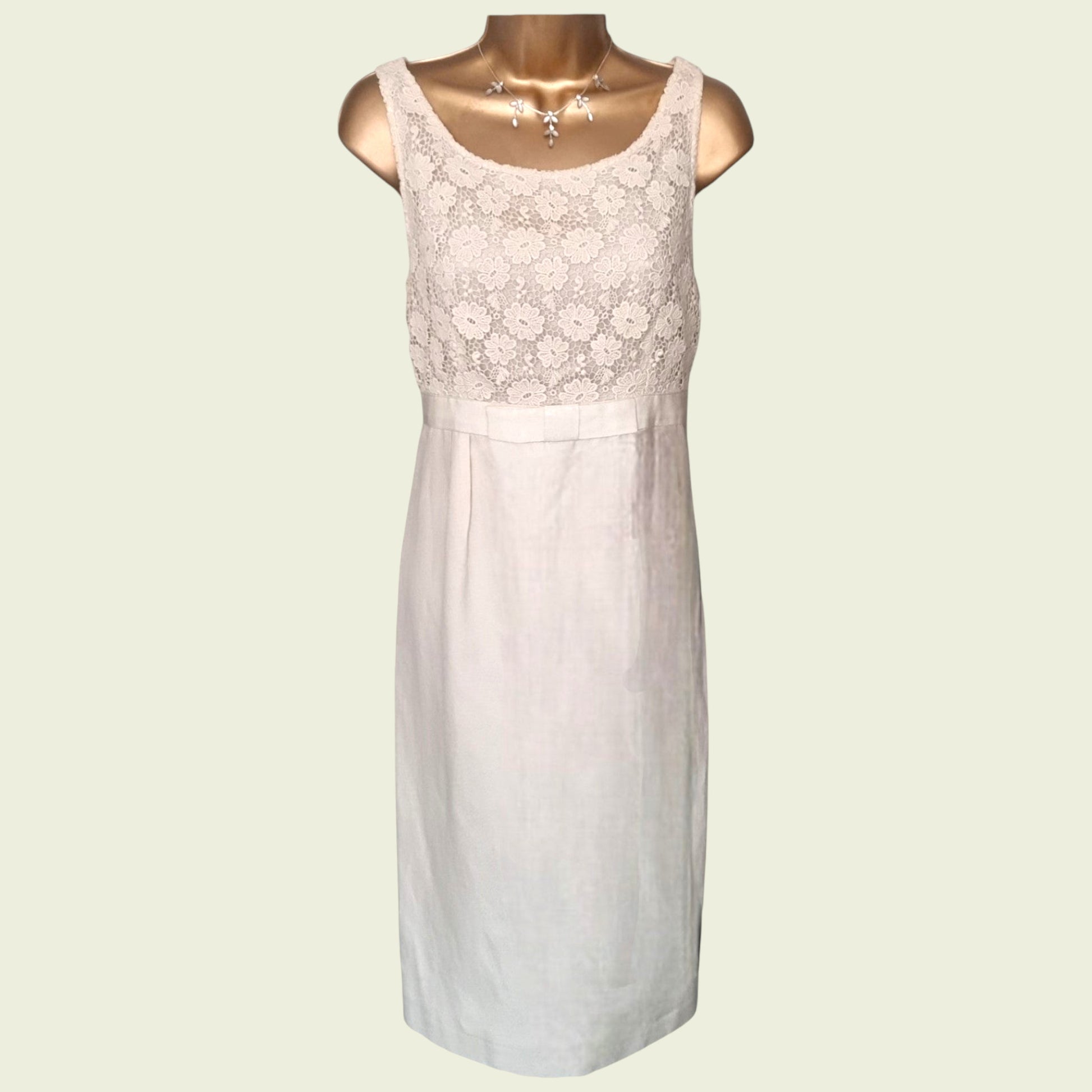 Mannequin wearing a cream dress with embroidered bodice on beige background