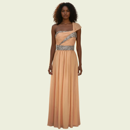 Woman wearing a peach evening gown with a silver embellished waistband on a beige background