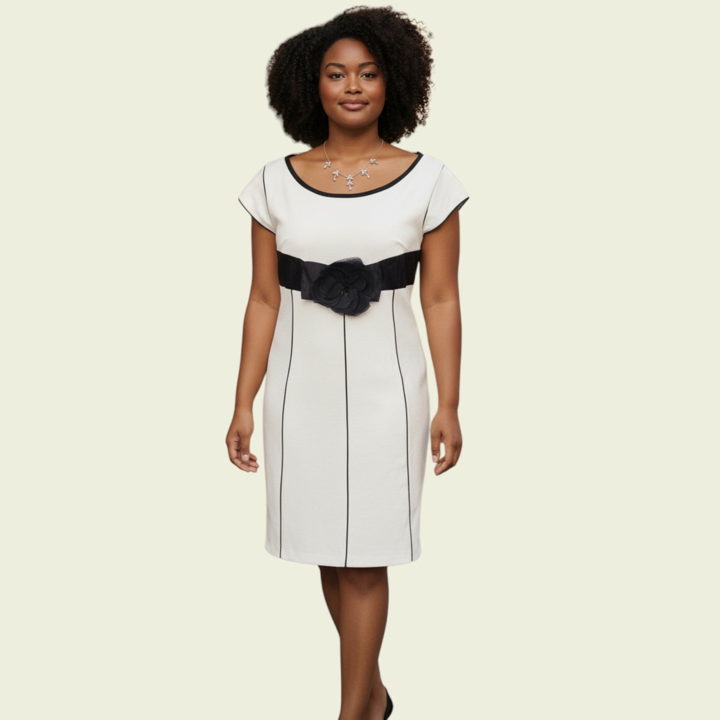 Woman wearing a white dress with a black sash on a beige background