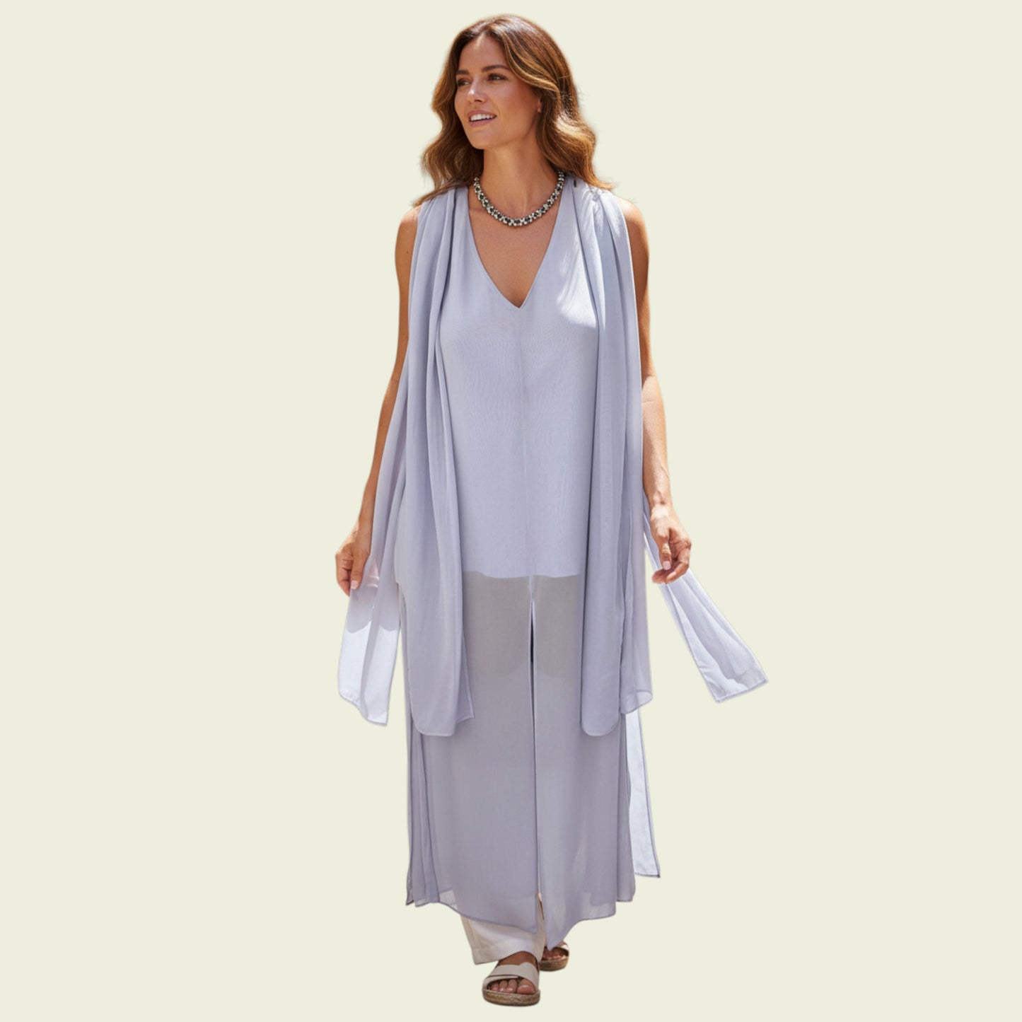 Woman wearing a light blue sleeveless top and gray pants with a matching scarf on a beige background