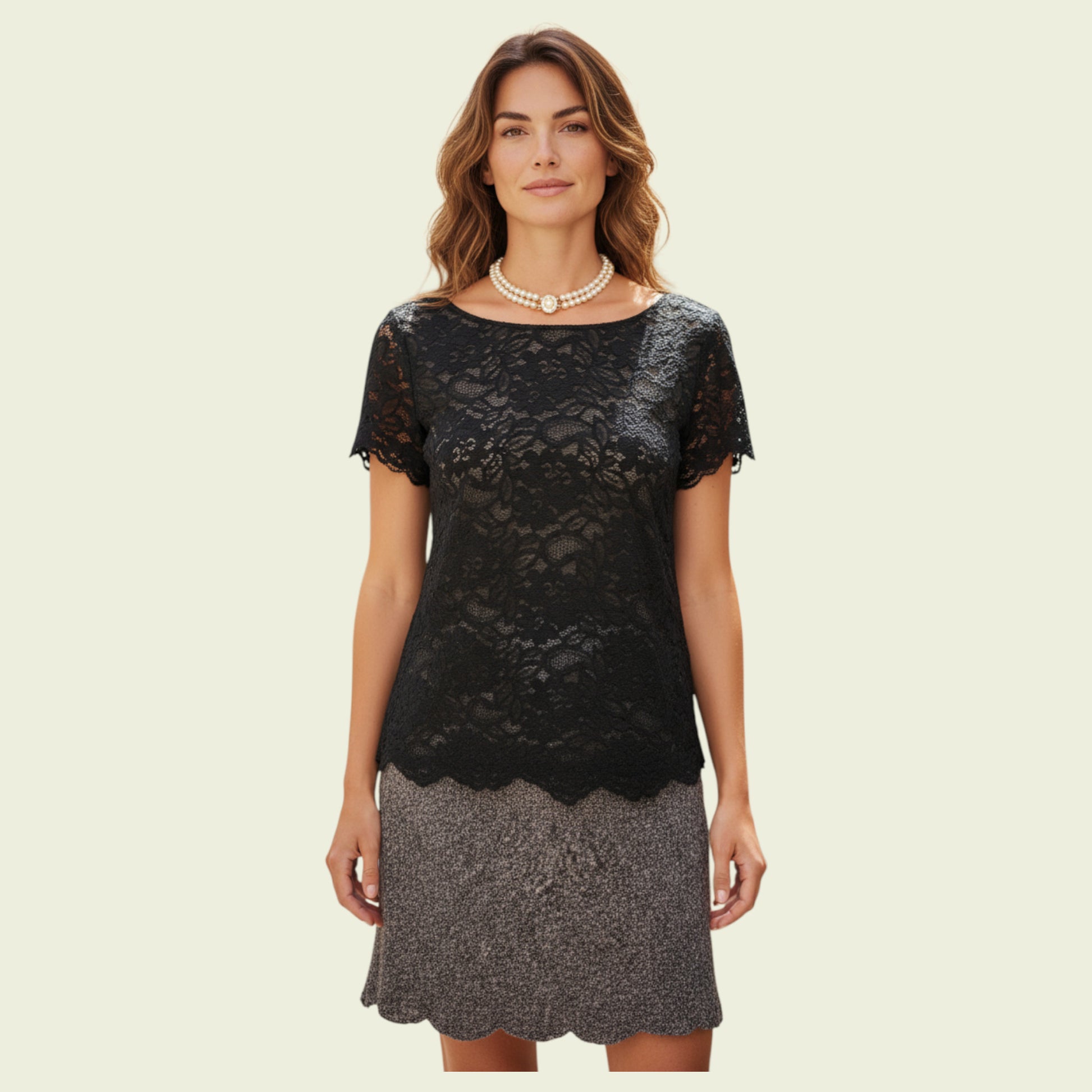 Woman wearing a black lace top and gray skirt on a beige background