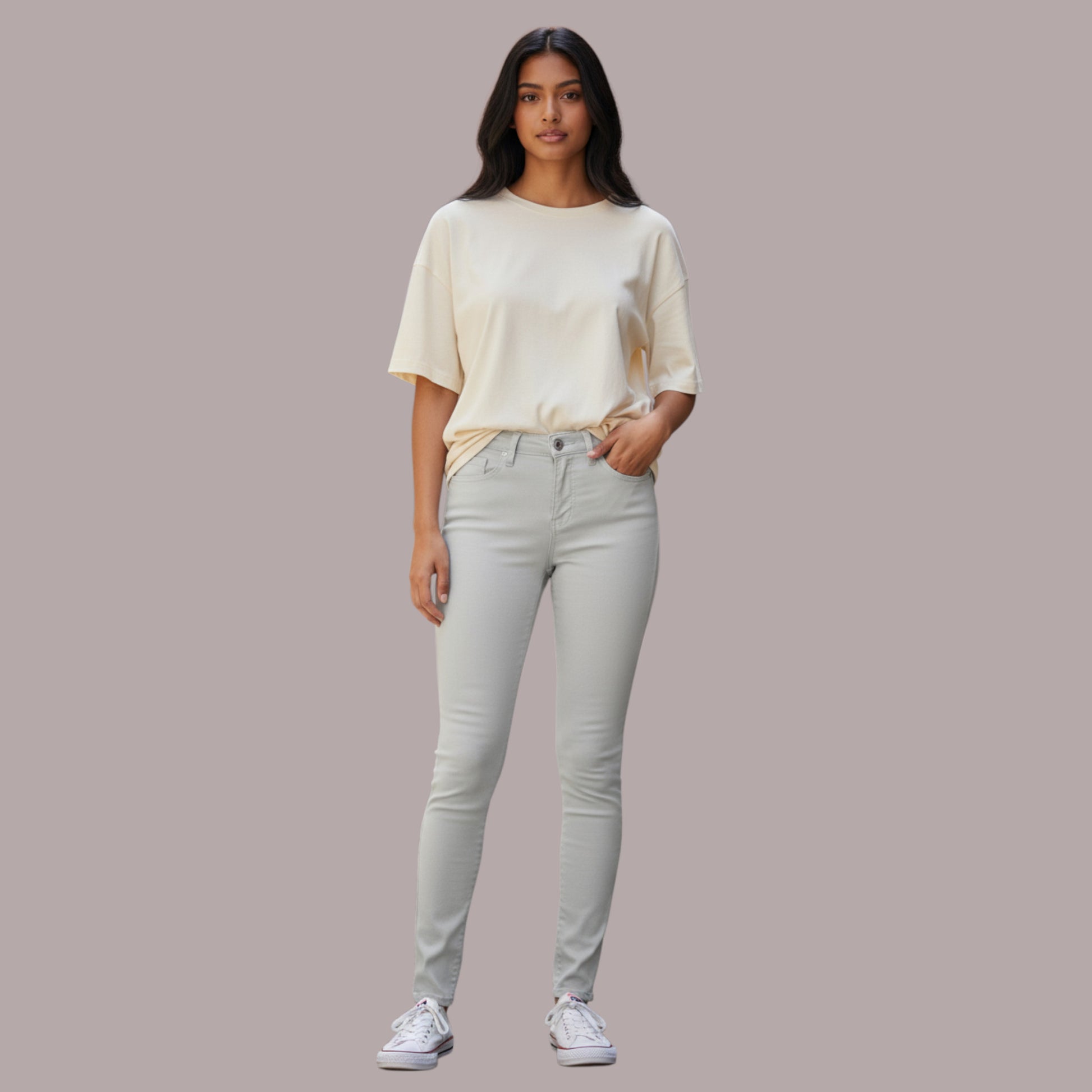 Woman wearing a light-colored top and gray pants on a plain background