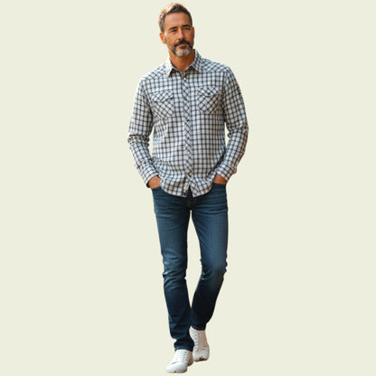 Model wearing plaid shirt and jeans on a light background