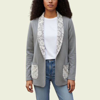 Woman wearing a gray blazer with floral lace details on a beige background
