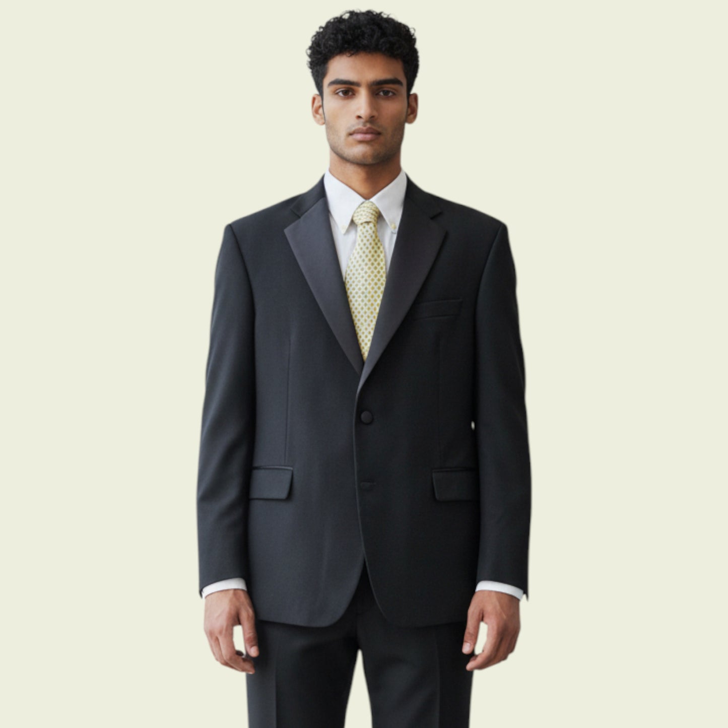 Man wearing a dark gray suit with a white shirt and patterned tie on a beige background