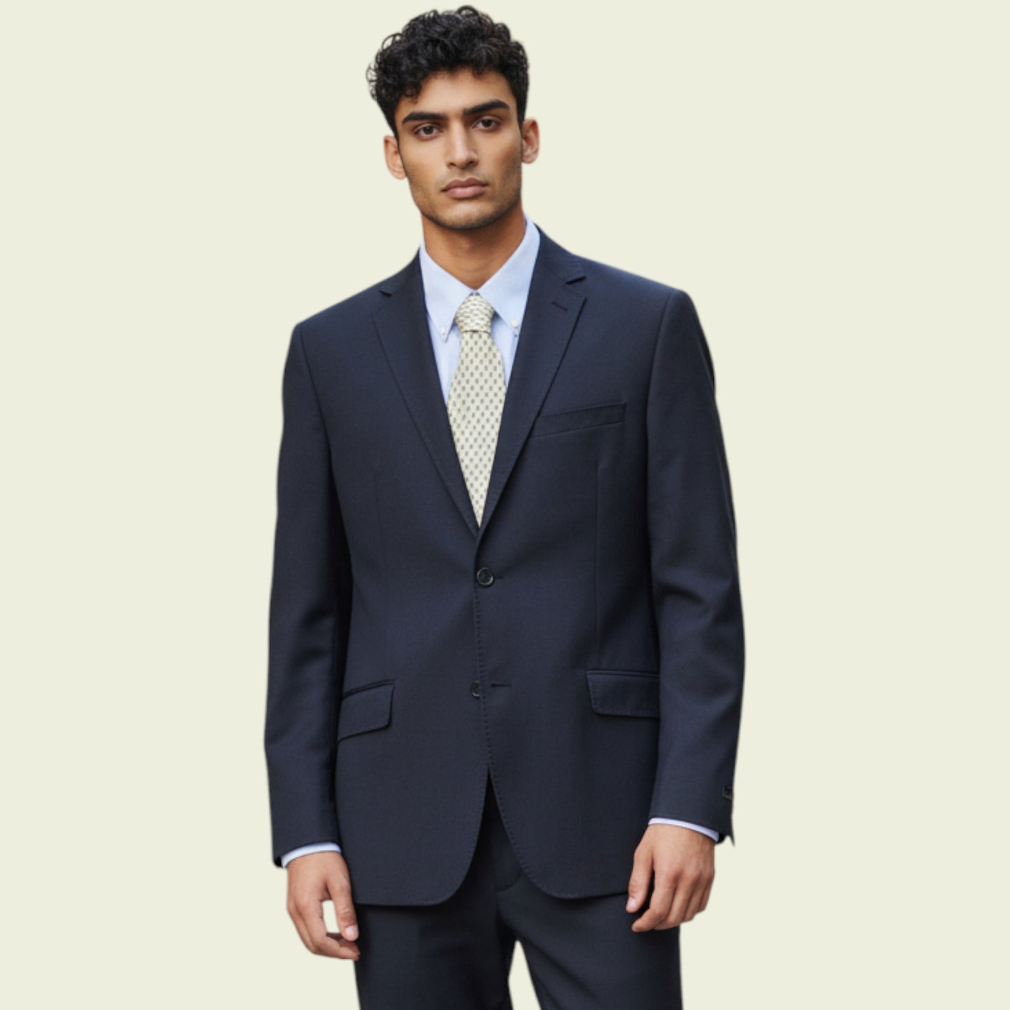 Man wearing a dark blue jacket with a light blue shirt and patterned tie on a beige background