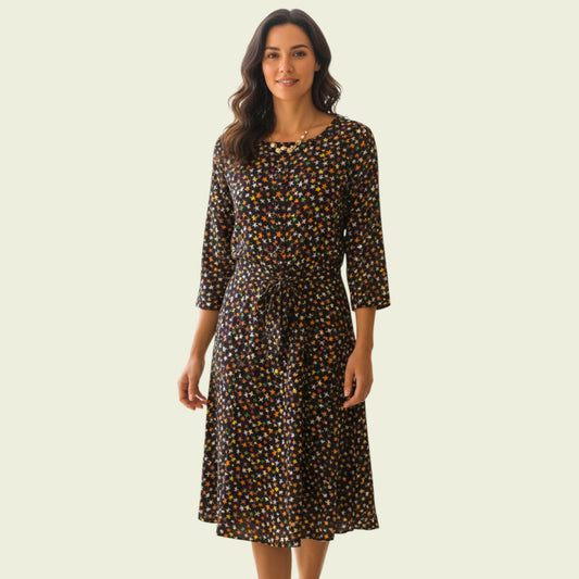 Model wearing black blouse and skirt with star pattern on beige background