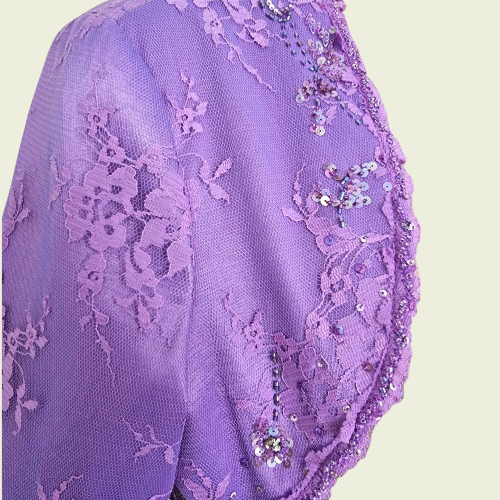 Purple lace fabric with floral patterns and sequins on a beige background