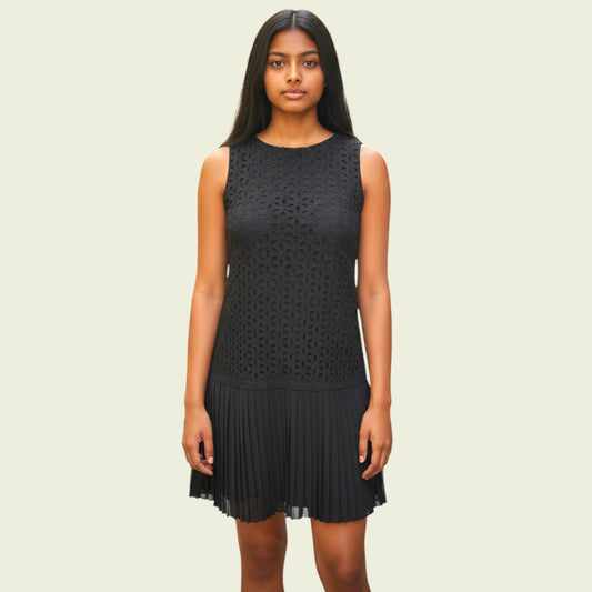 Woman wearing a black sleeveless dress with geometric pattern on a beige background