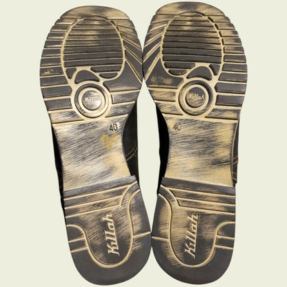 View of boot soles showing wear on beige background