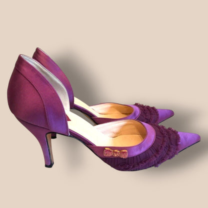 Purple high-heeled shoes with ruffled details on a beige background