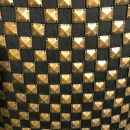 Close-up of a patterned fabric with gold and black diamond shapes.