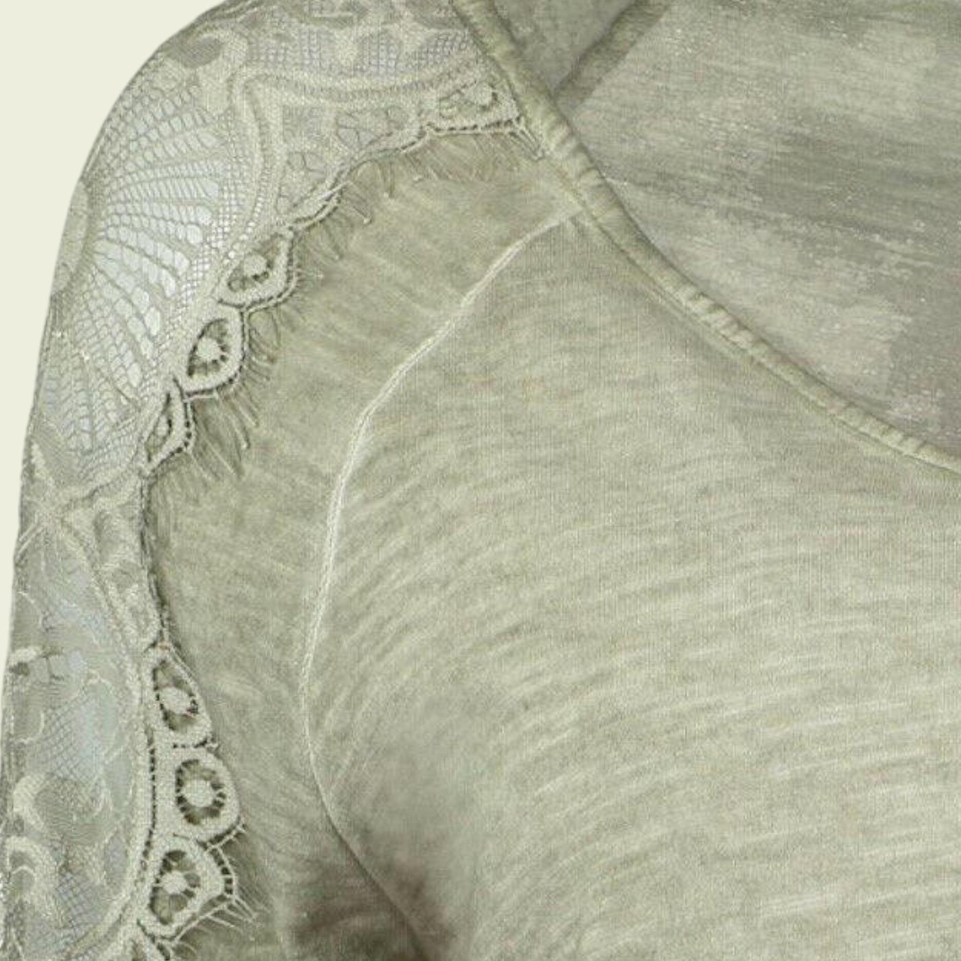 Close-up of a light green garment with lace detailing on a beige background