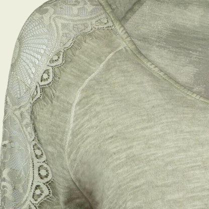 Close-up of a light green garment with lace detailing on a beige background