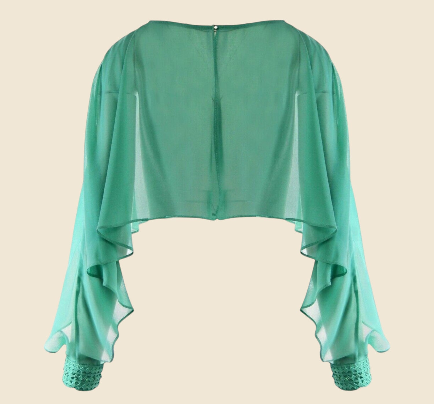Green sheer top with lace cuffs on a beige background